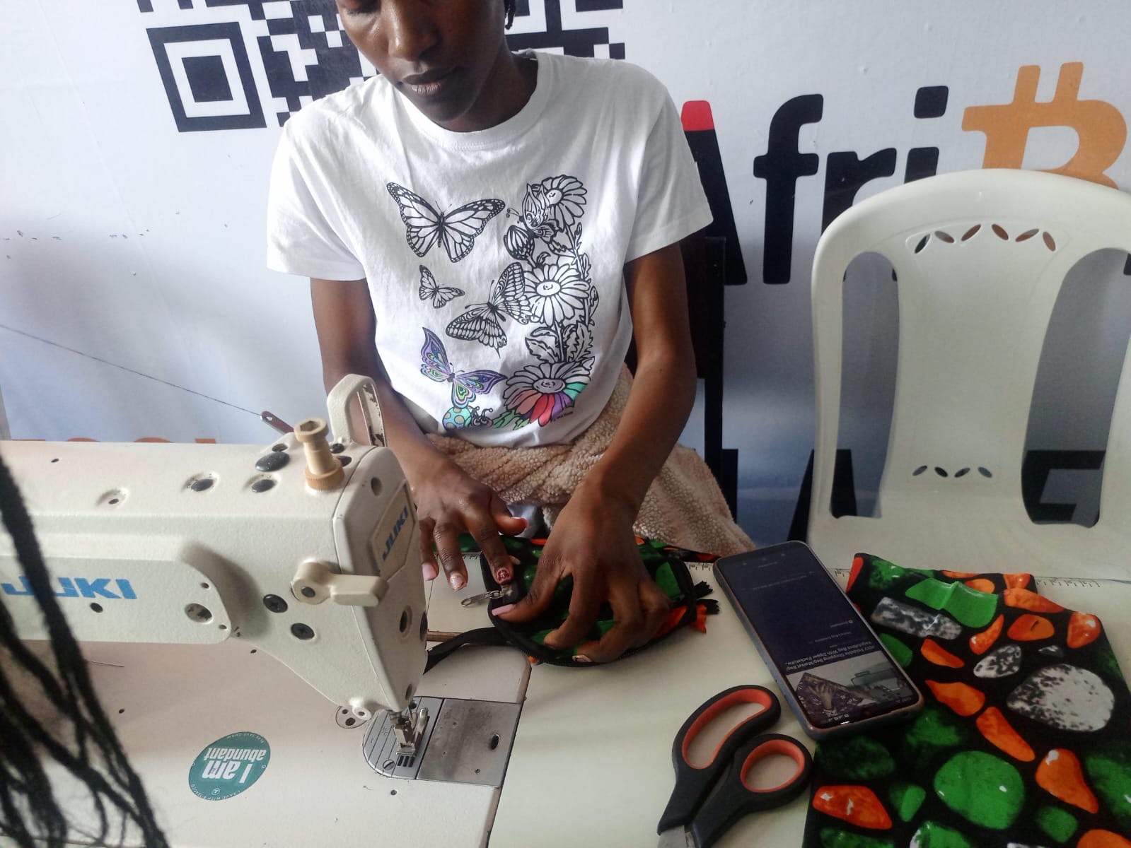 A worker handling patterned fabric beside a sewing machine in Kenya.